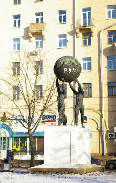 two statues of a man holding a ball on their head
