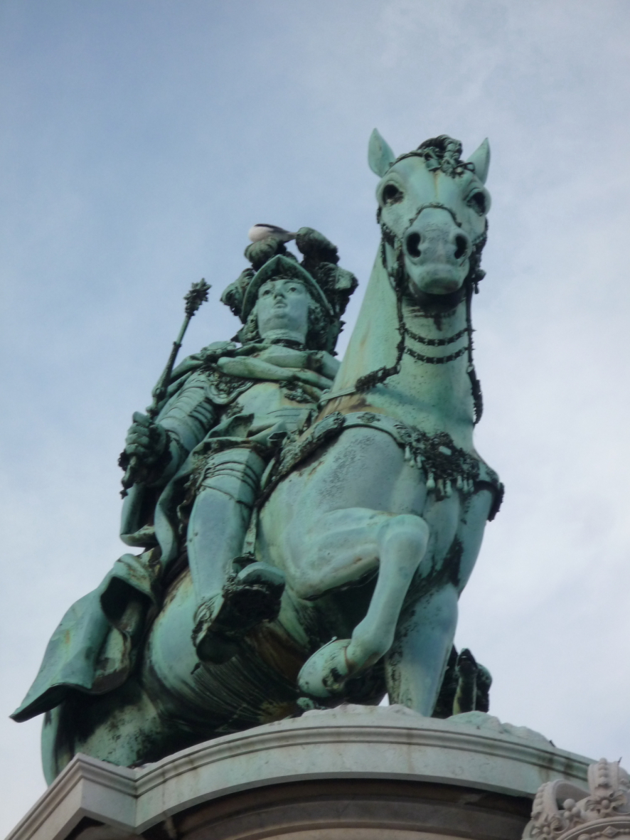 two statues depicting men on horses standing on top of a building