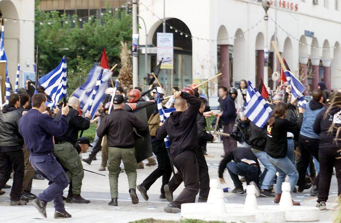 many protesters on the street, some in black holding flags