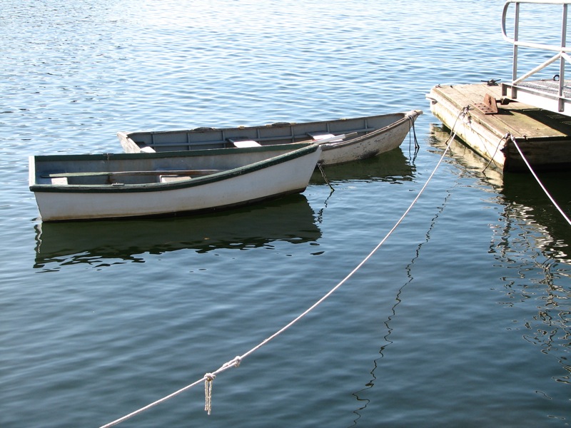 two small boats on the water next to a dock