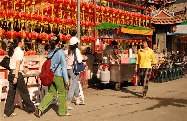 people walking past a street vendors in an oriental city
