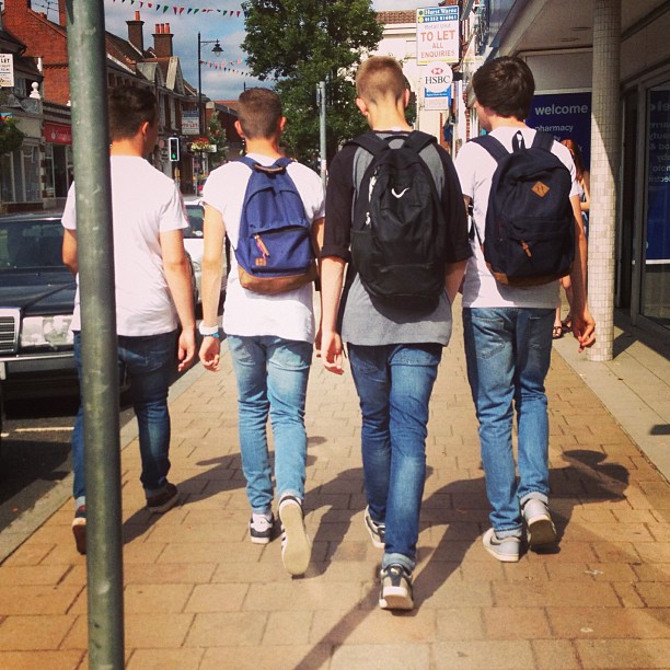 four boys walking down the street carrying school bags