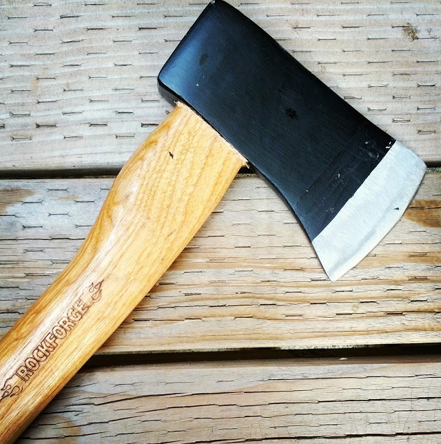 an axe with wooden handle laying on top of a bench