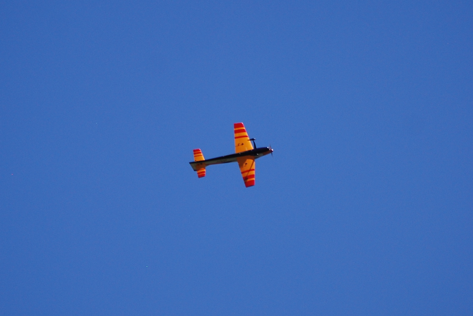 a biplane flying high in the sky with bright orange stripes