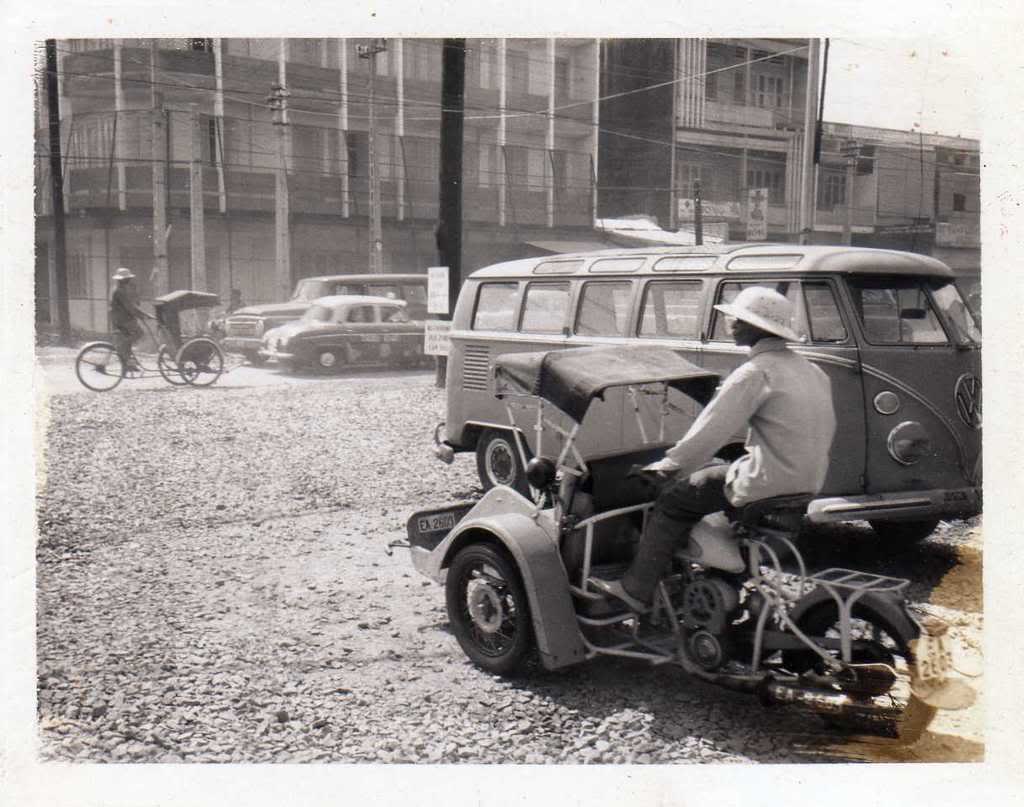 an old pograph of a person riding a motorcycle in front of a van