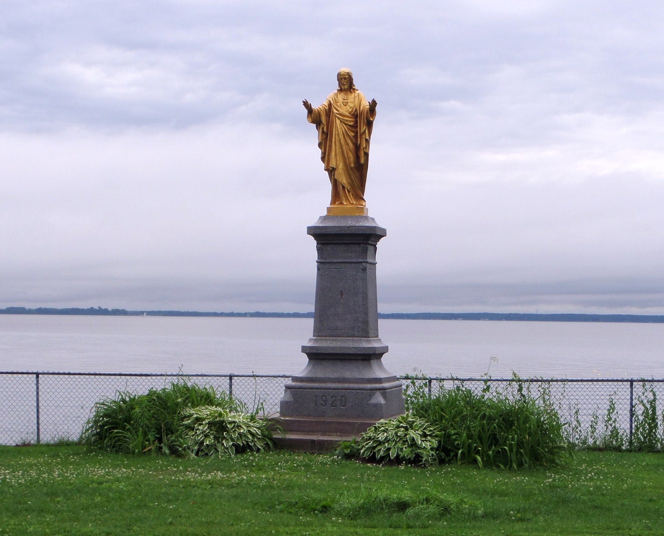 an image of a statue of jesus overlooking a body of water