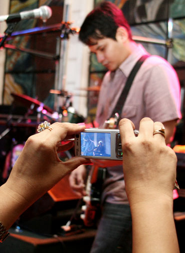 two people using cell phones to record a band