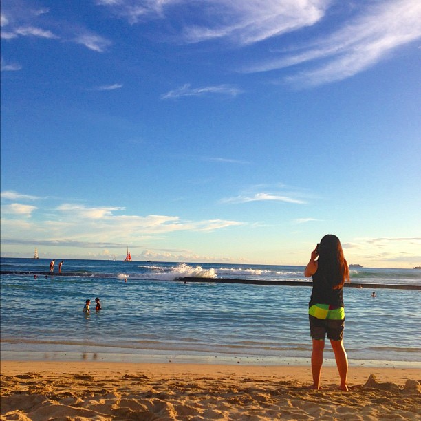 a woman standing on top of a sandy beach near the ocean