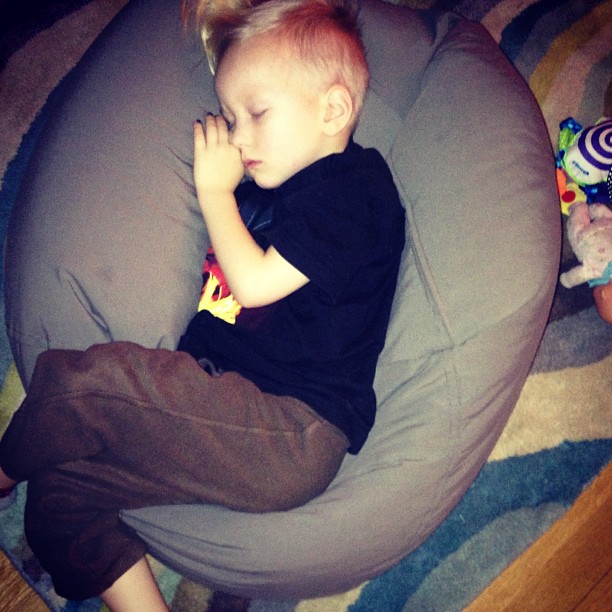 the small child is laying down on the bean bag chair