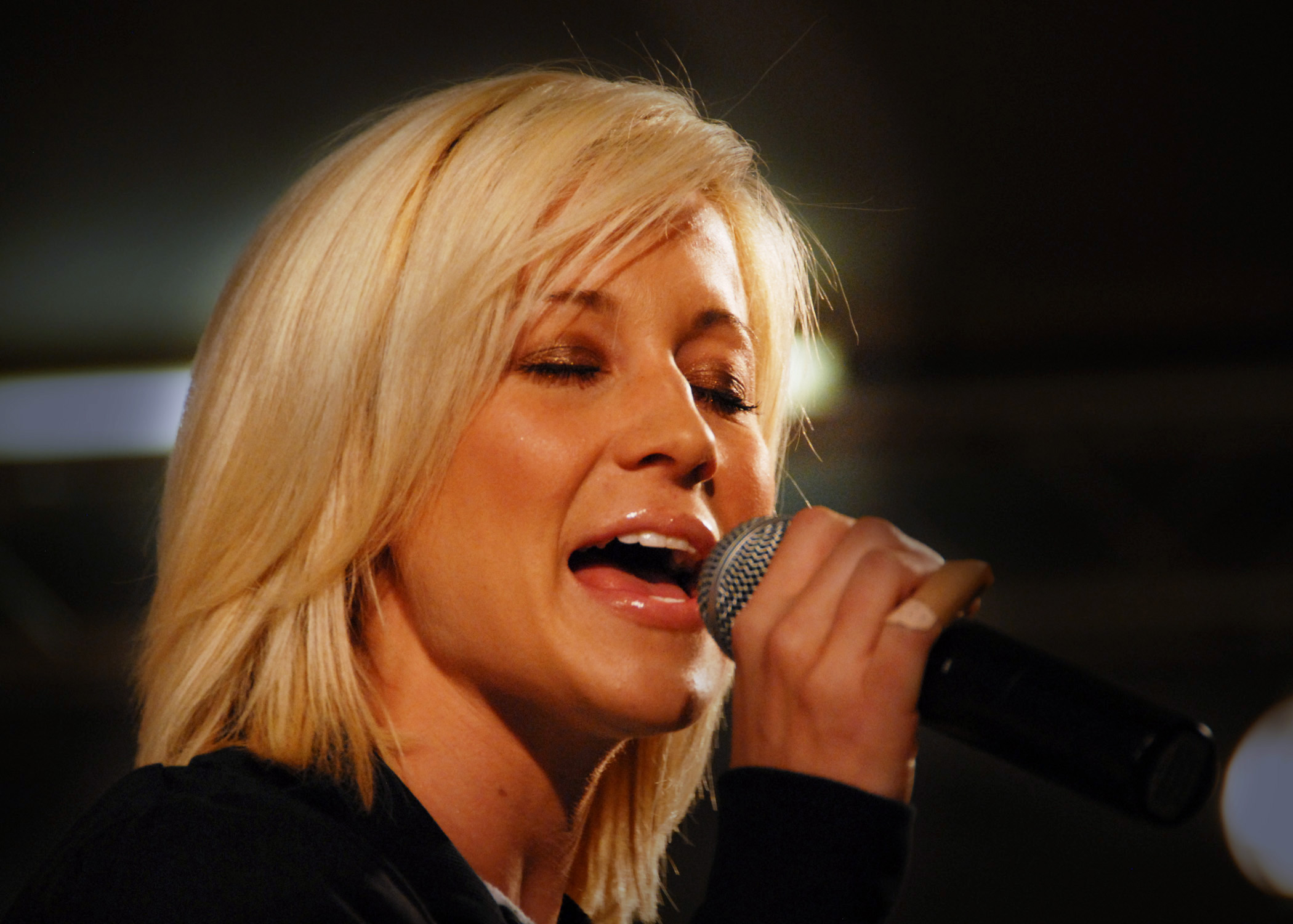 a blond woman singing into a microphone