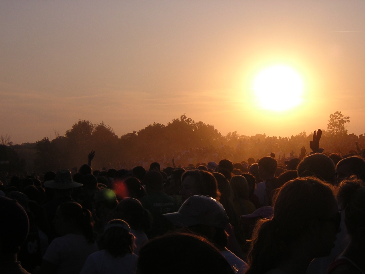 the sun rising behind a crowd of people