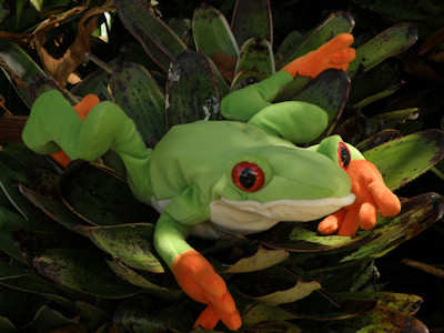 a green frog is sitting on some leaves