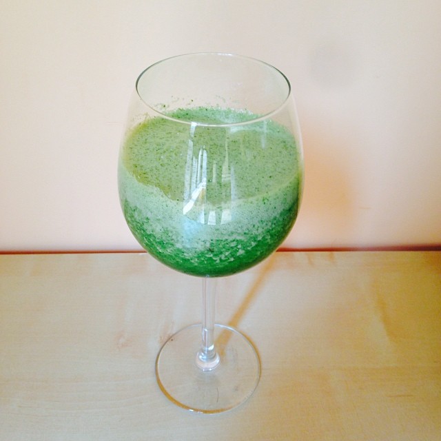 a green liquid in a large glass that is on a table