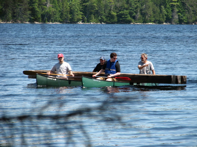 three people are rowing a canoe on the water