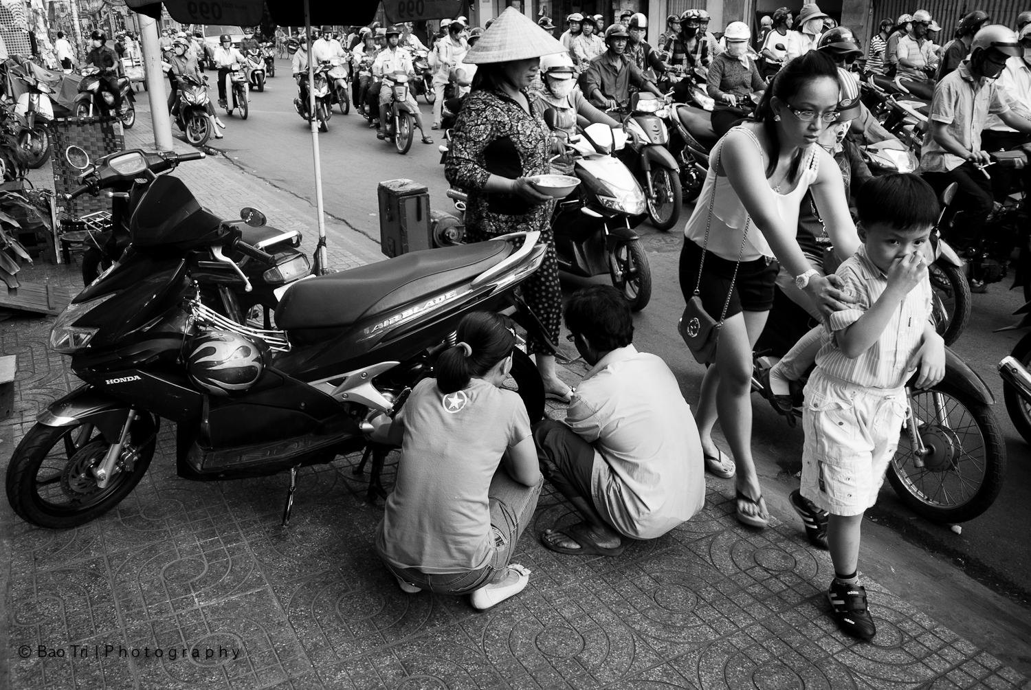 a bunch of people on the street and some are checking out a motorcycle