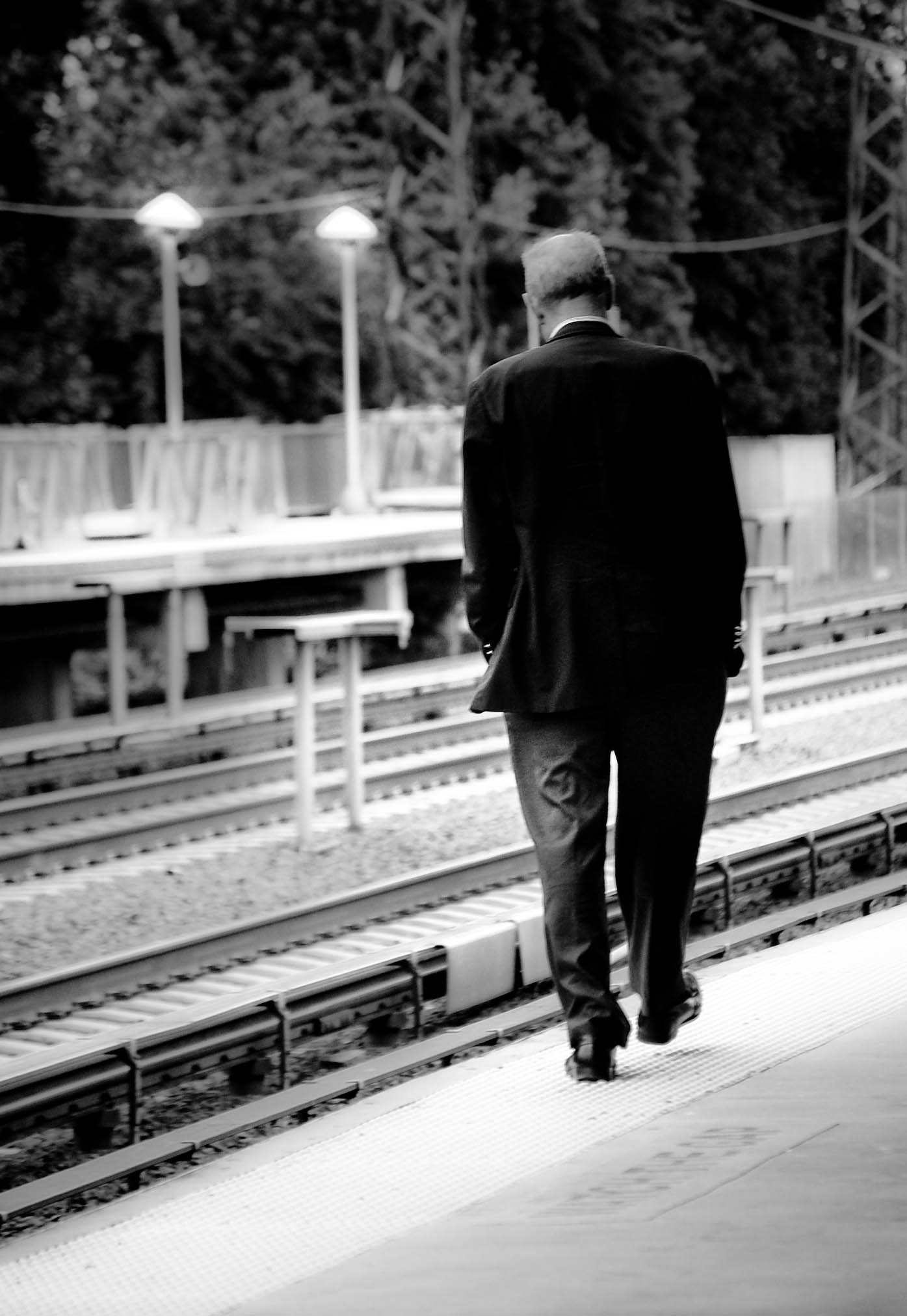 a man in suit walks away from the train tracks