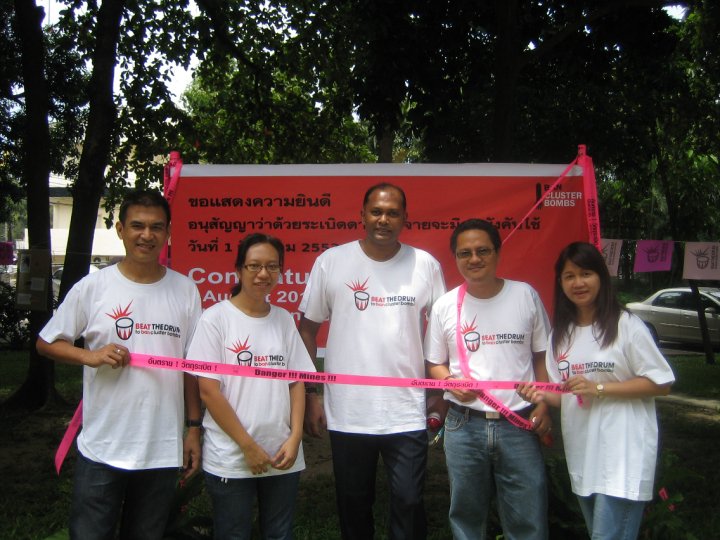a group of people holding a ribbon in front of a red banner