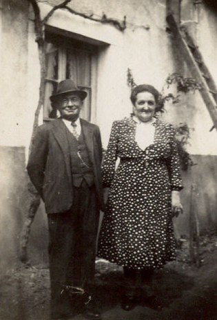 an old black and white po of two people standing outside of a house