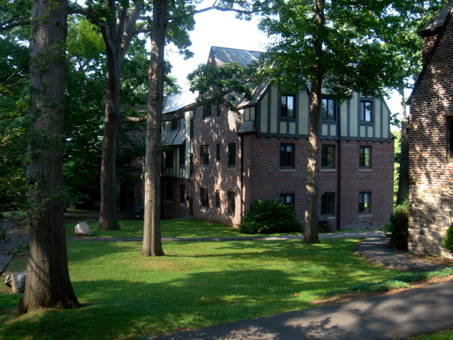 a brown brick building with tall windows next to trees