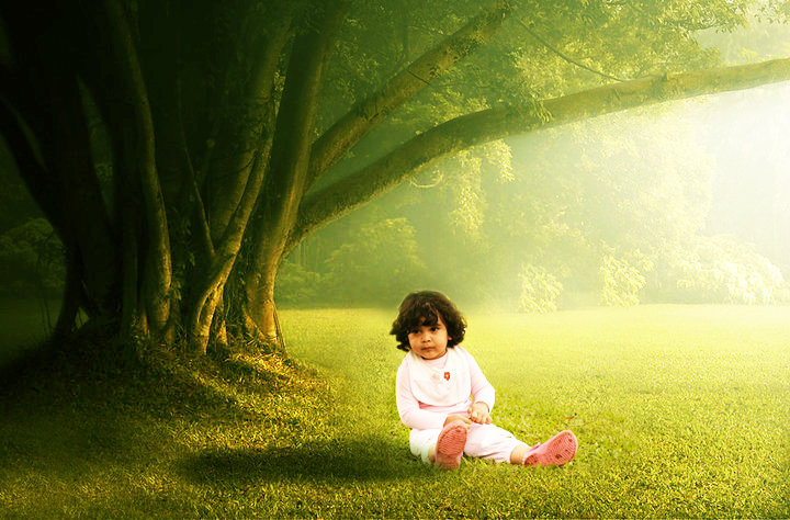 a little girl sits under a tree on the grass