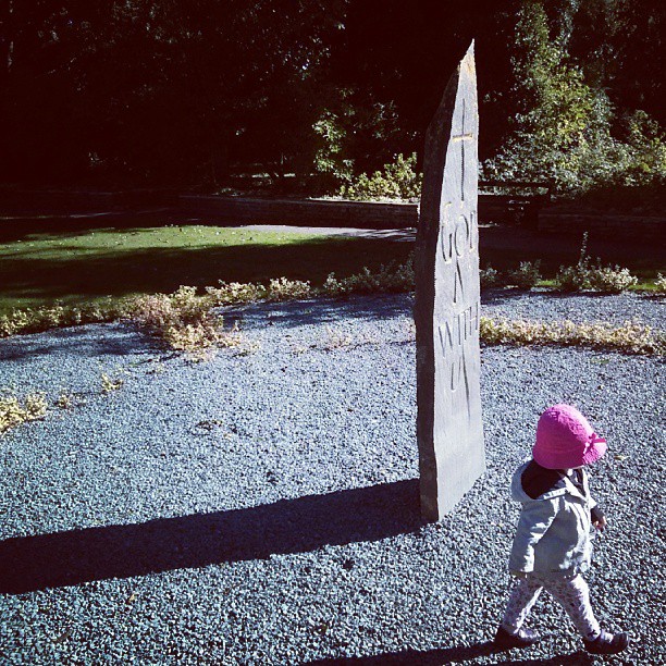 a small child in pink hat walking by a sign