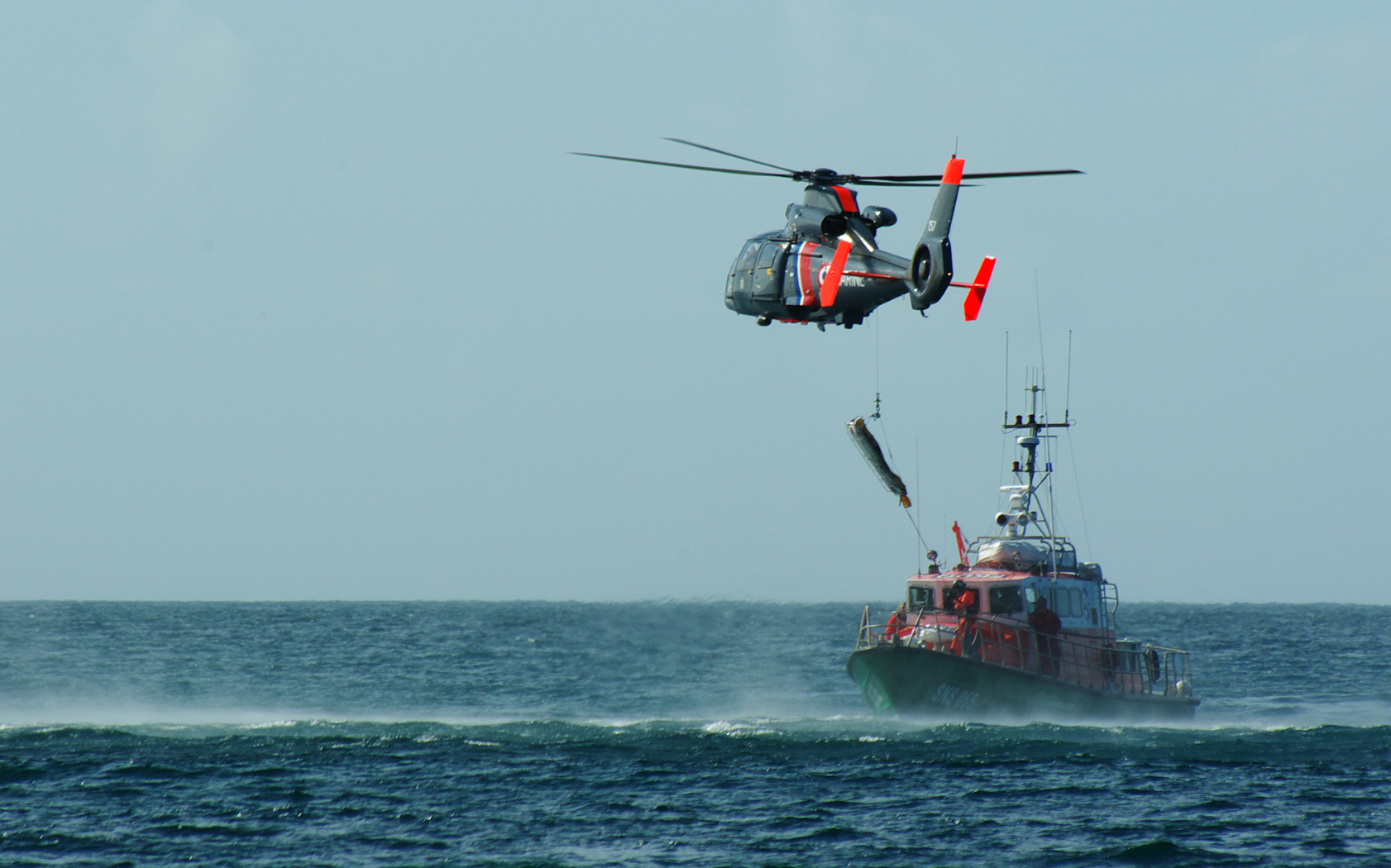 a helicopter flying over a boat floating in a ocean