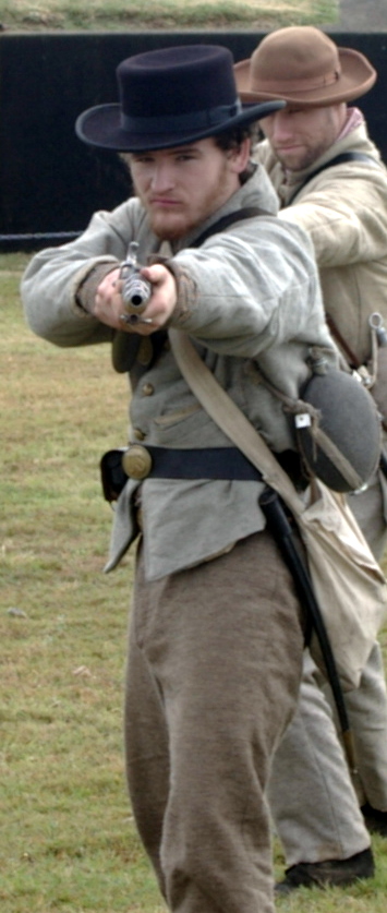 two men dressed in historical period clothing aiming with their arms