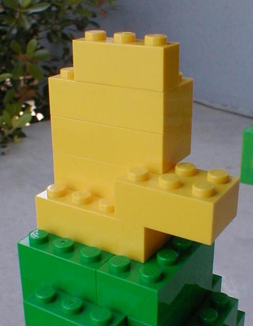 a lego tower sits on top of a small brick block wall
