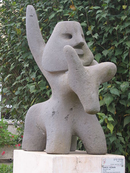 a grey statue of a cat near some bushes