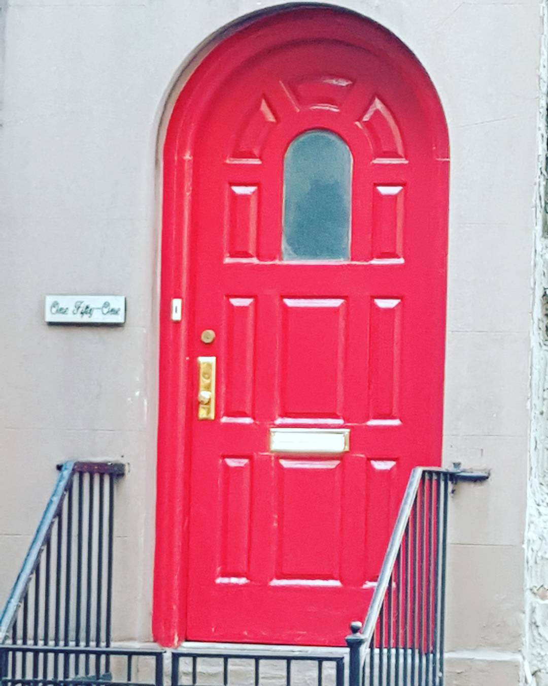 a red door on the side of a building with iron gates