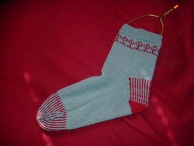 a sock that is hanging on a red pillow
