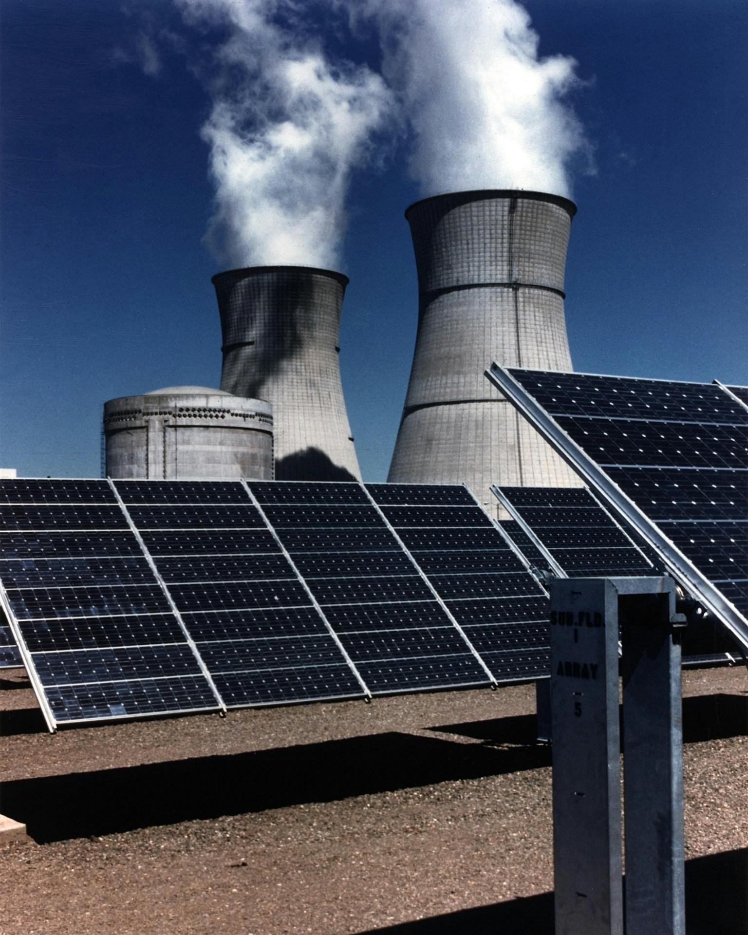 a group of solar panels sitting on top of a dirt field, a colorized photo, pexels contest winner, nuclear art, power plants with smoke, promo image, on a dark background, taken in the late 2010s