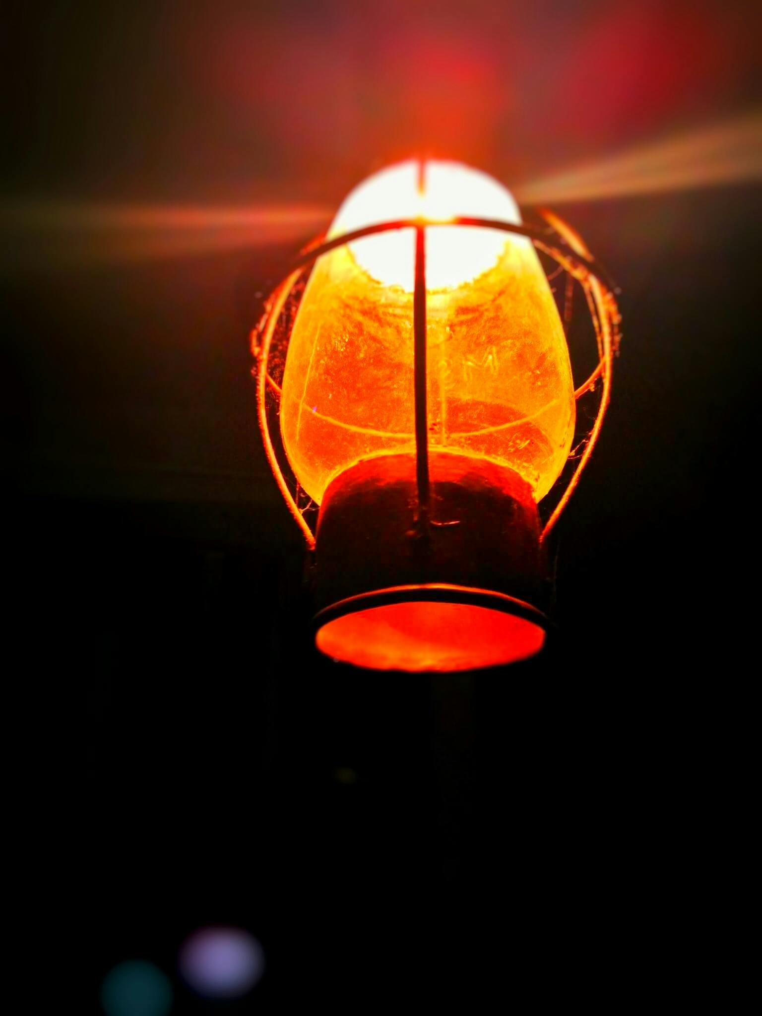 a close up of a light in the dark, light red and orange mood, dim lantern, an upright lightbulb, it's dark