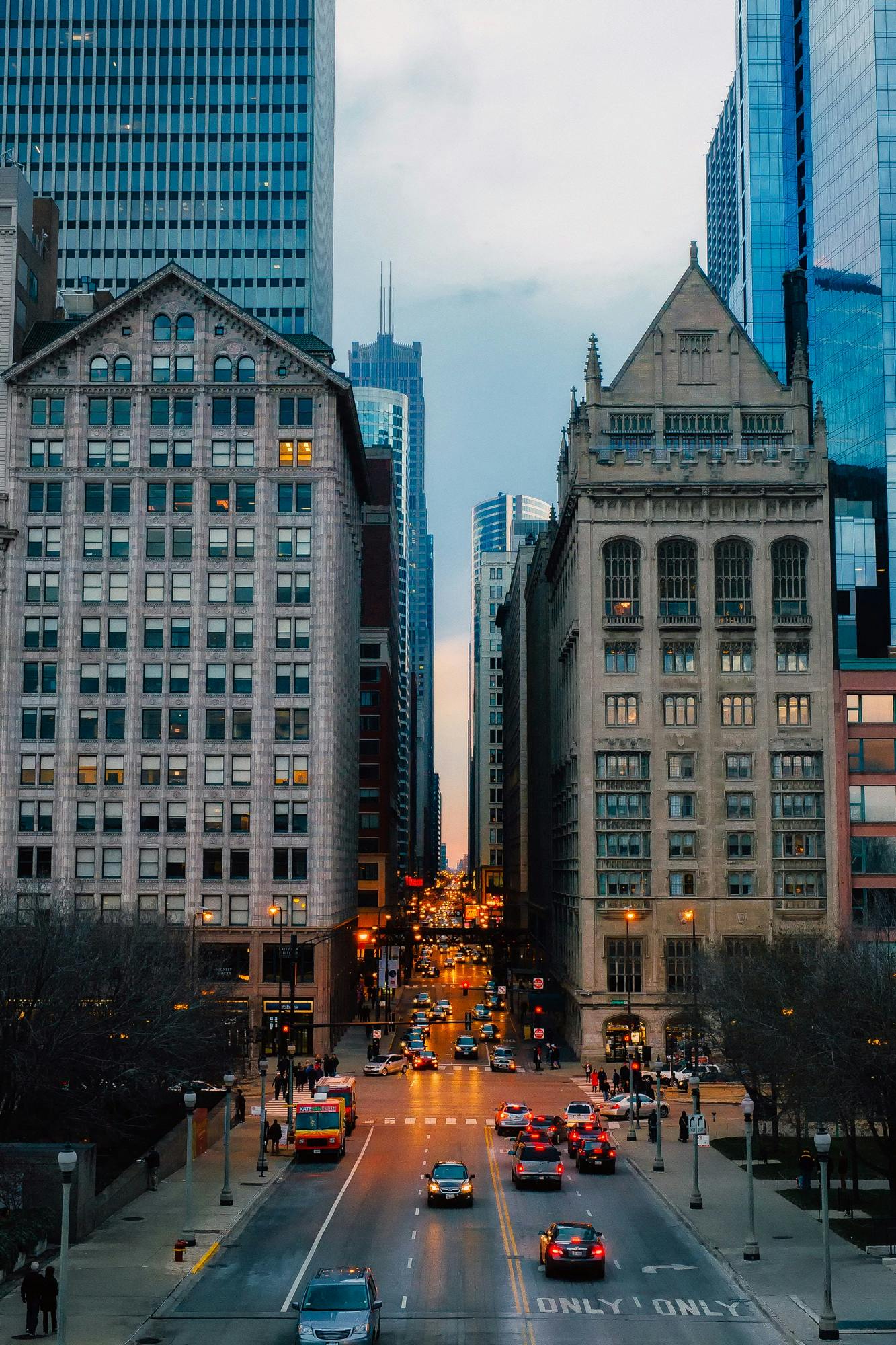 a city street filled with lots of tall buildings, by Greg Rutkowski, pexels contest winner, renaissance, from wheaton illinois, early evening, neo - gothic architecture, chicago