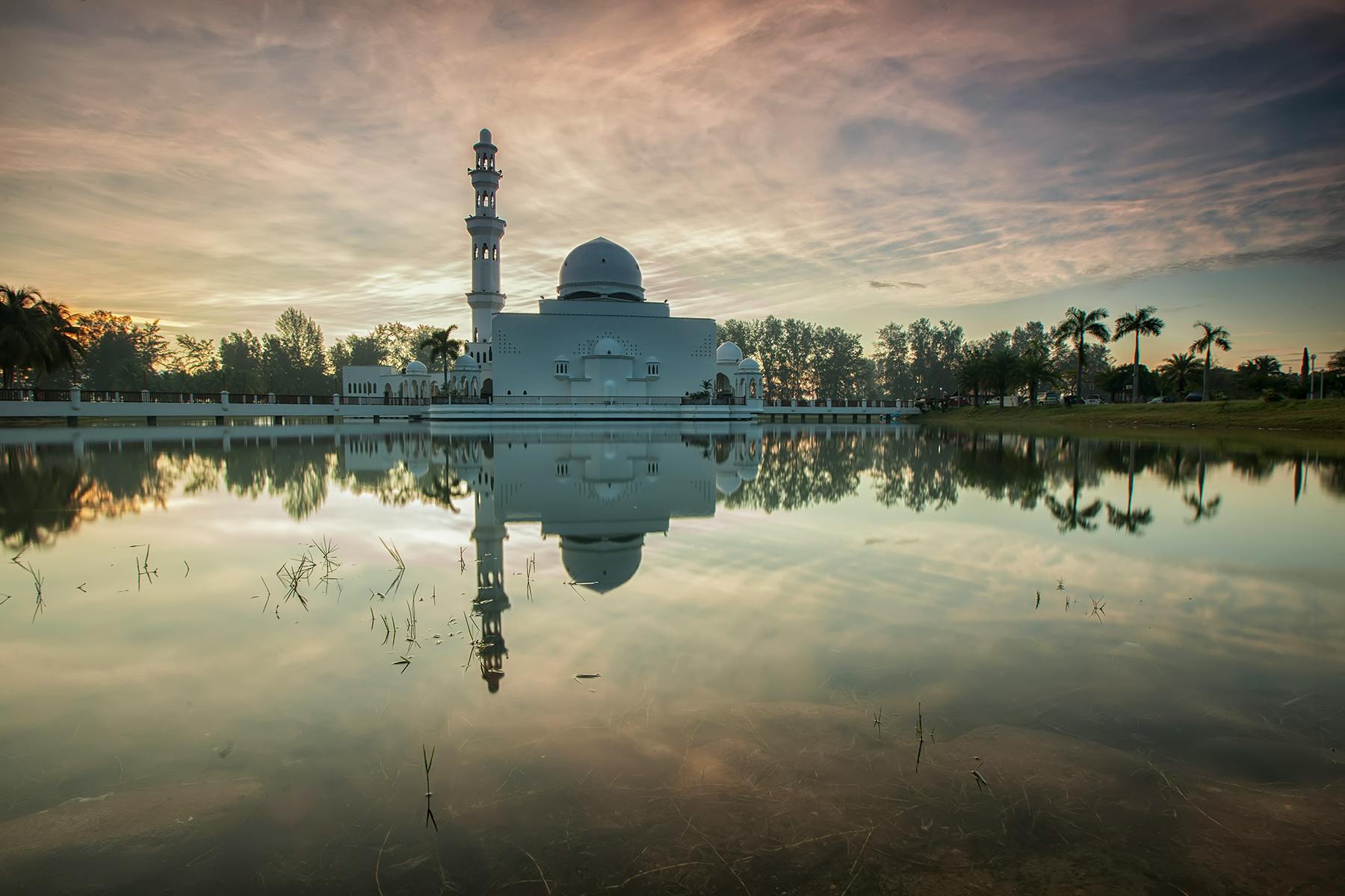 a large white building sitting next to a body of water, a picture, by Bernardino Mei, unsplash contest winner, hurufiyya, mausoleum, malaysian, reflective ground, at the sunset
