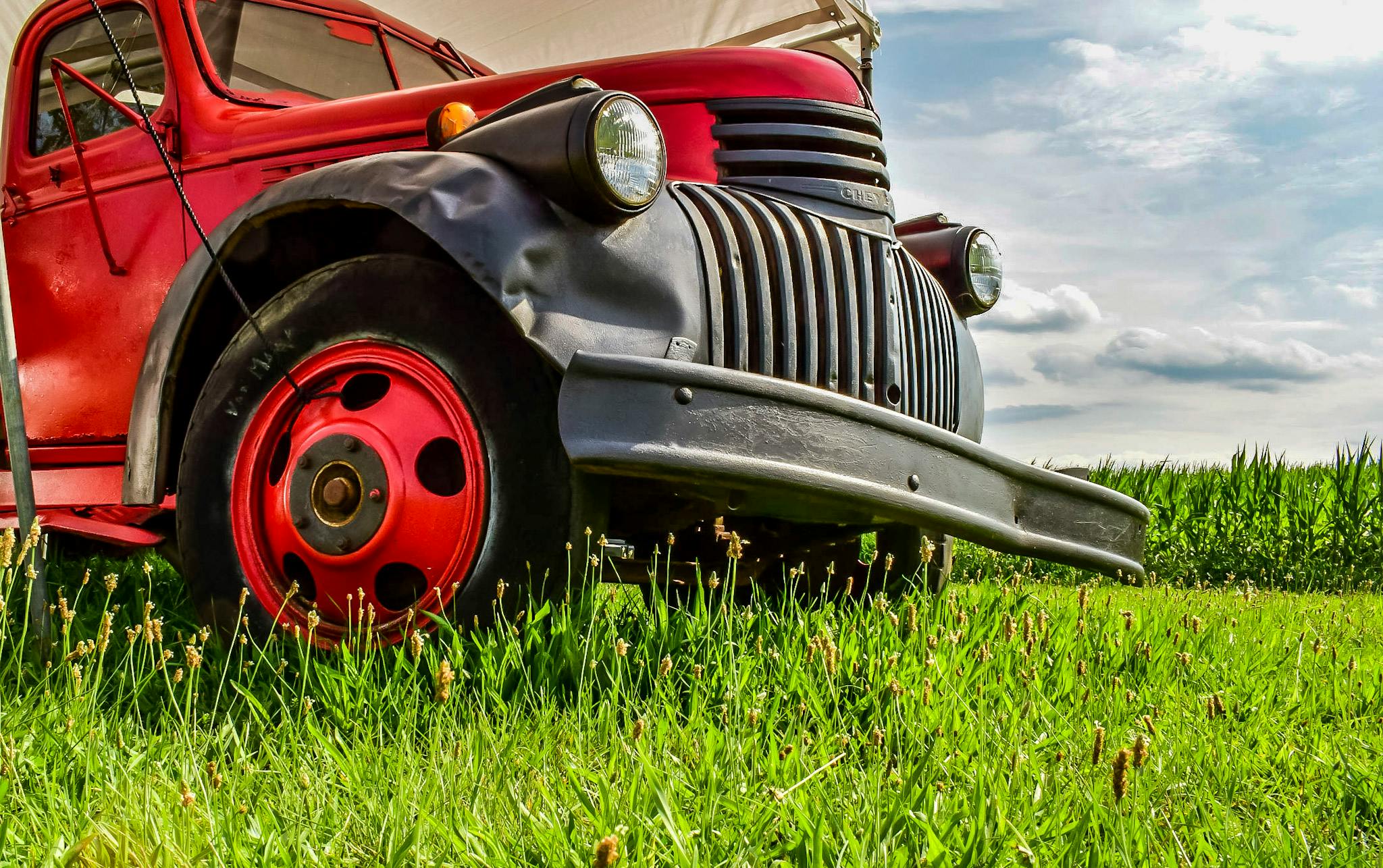 a red truck sitting on top of a lush green field, pexels contest winner, auto-destructive art, with a lush grass lawn, driving a hotrod, dynamic closeup, today\'s featured photograph 4k