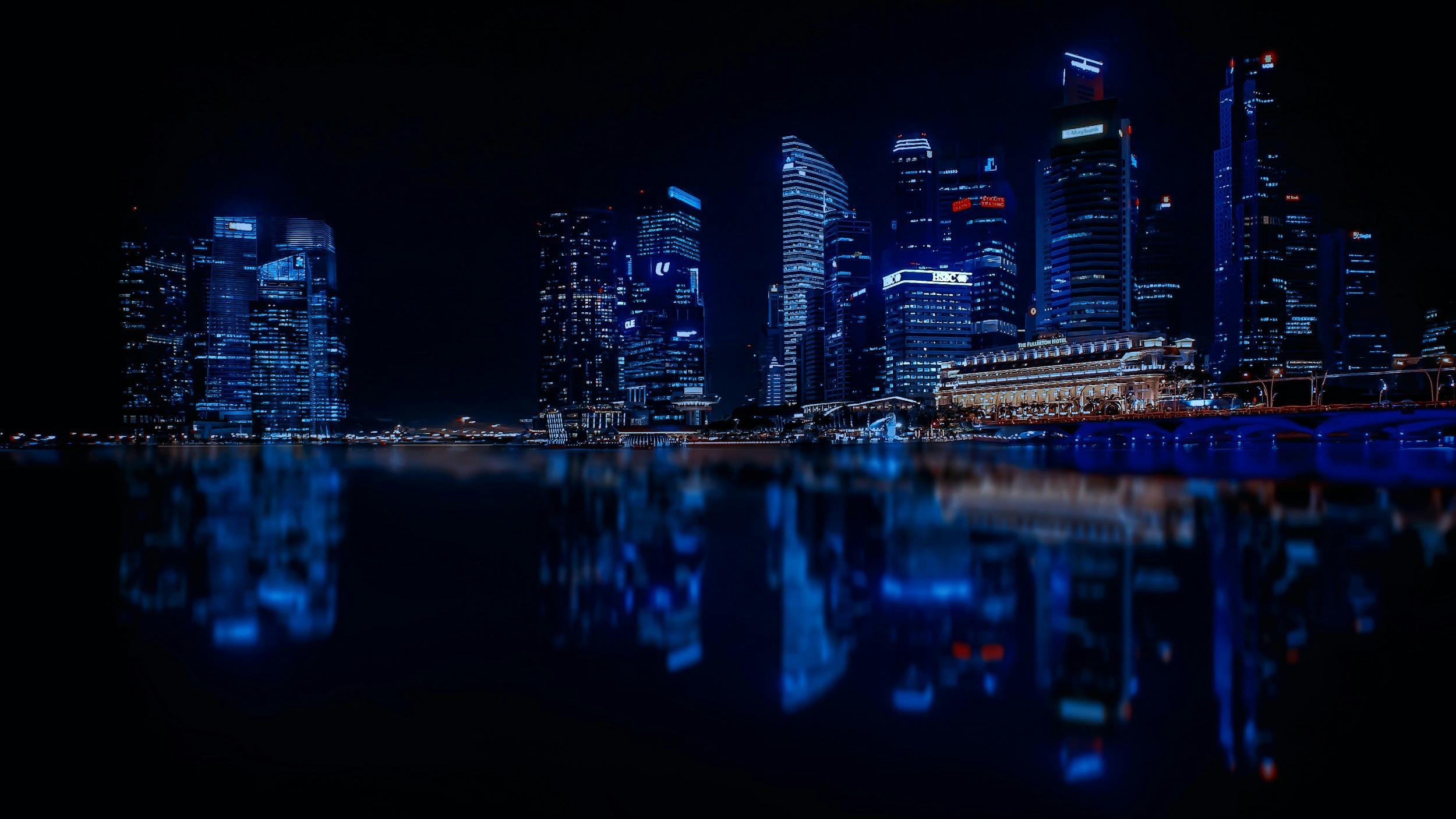 a view of a city at night from across the water, by Patrick Ching, pexels contest winner, hyperrealism, symmetrical shot, glowing blue, singapore city, hyperrealistic image