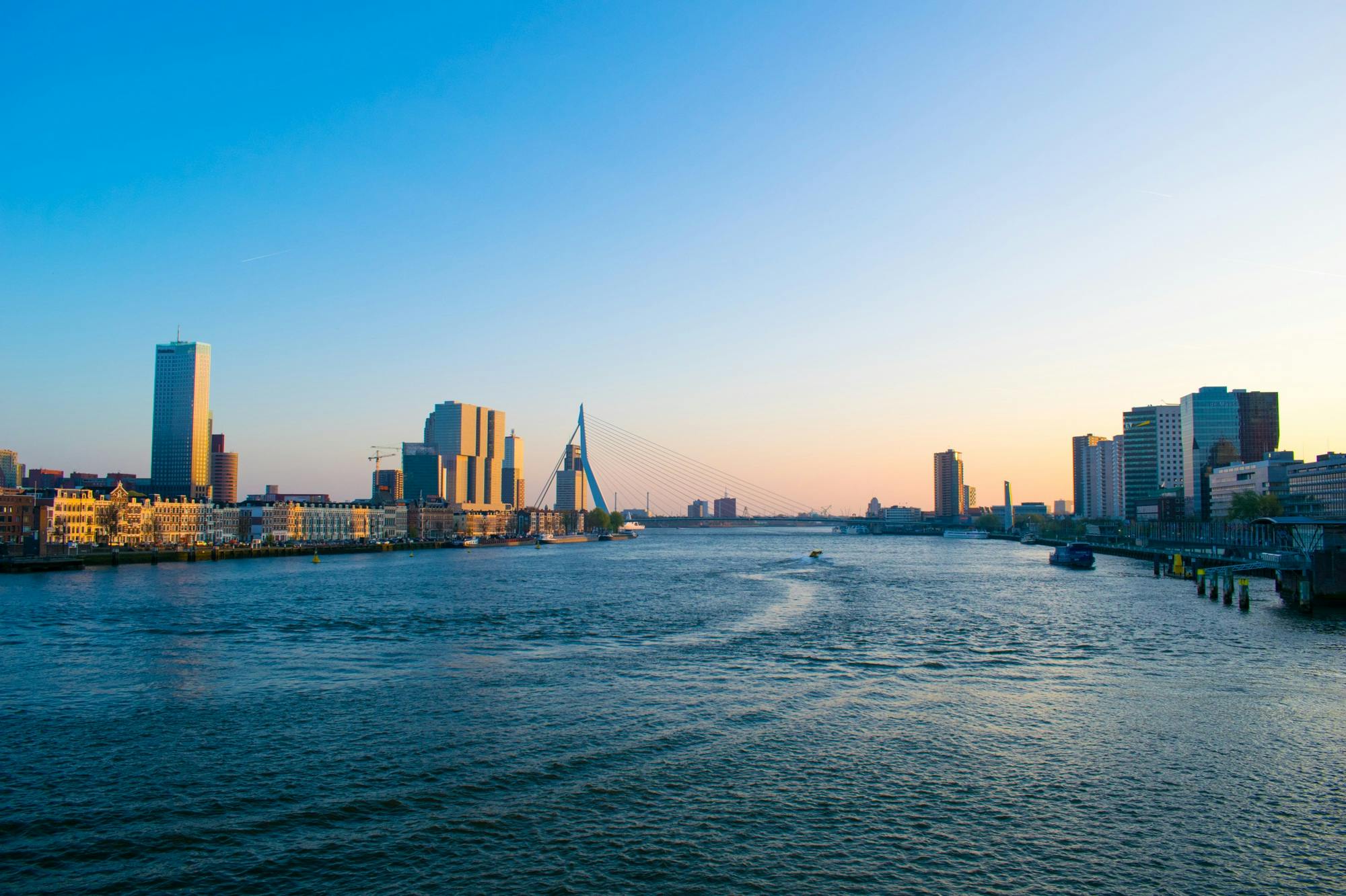 a large body of water with a city in the background, by Jacob Toorenvliet, pexels contest winner, happening, helmond, datapipeline or river, sunny environment, late afternoon