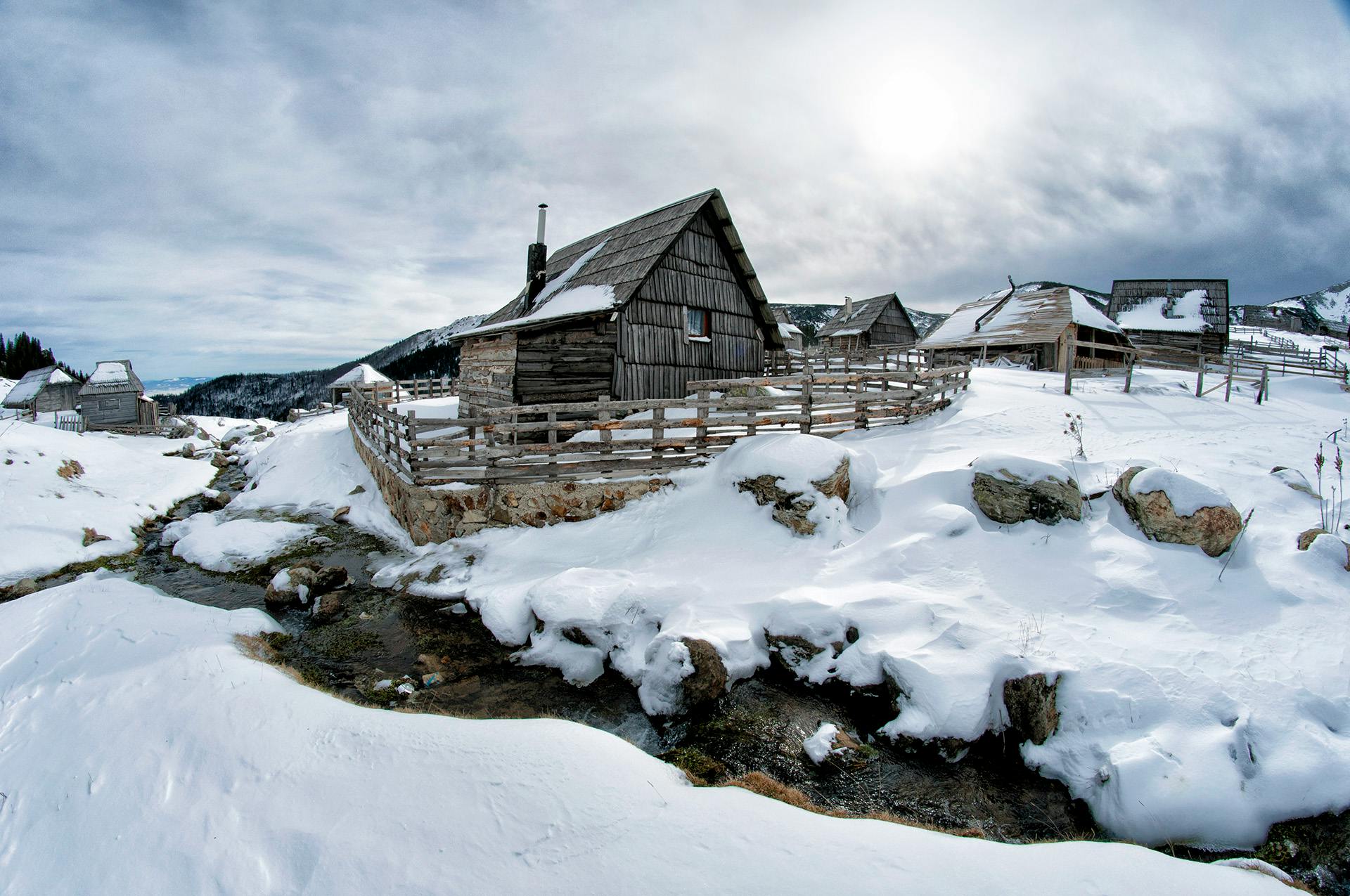 a wooden cabin sitting on top of a snow covered slope, by Ivan Grohar, pexels contest winner, renaissance, peaked wooden roofs, panoramic, album cover, old lumber mill remains