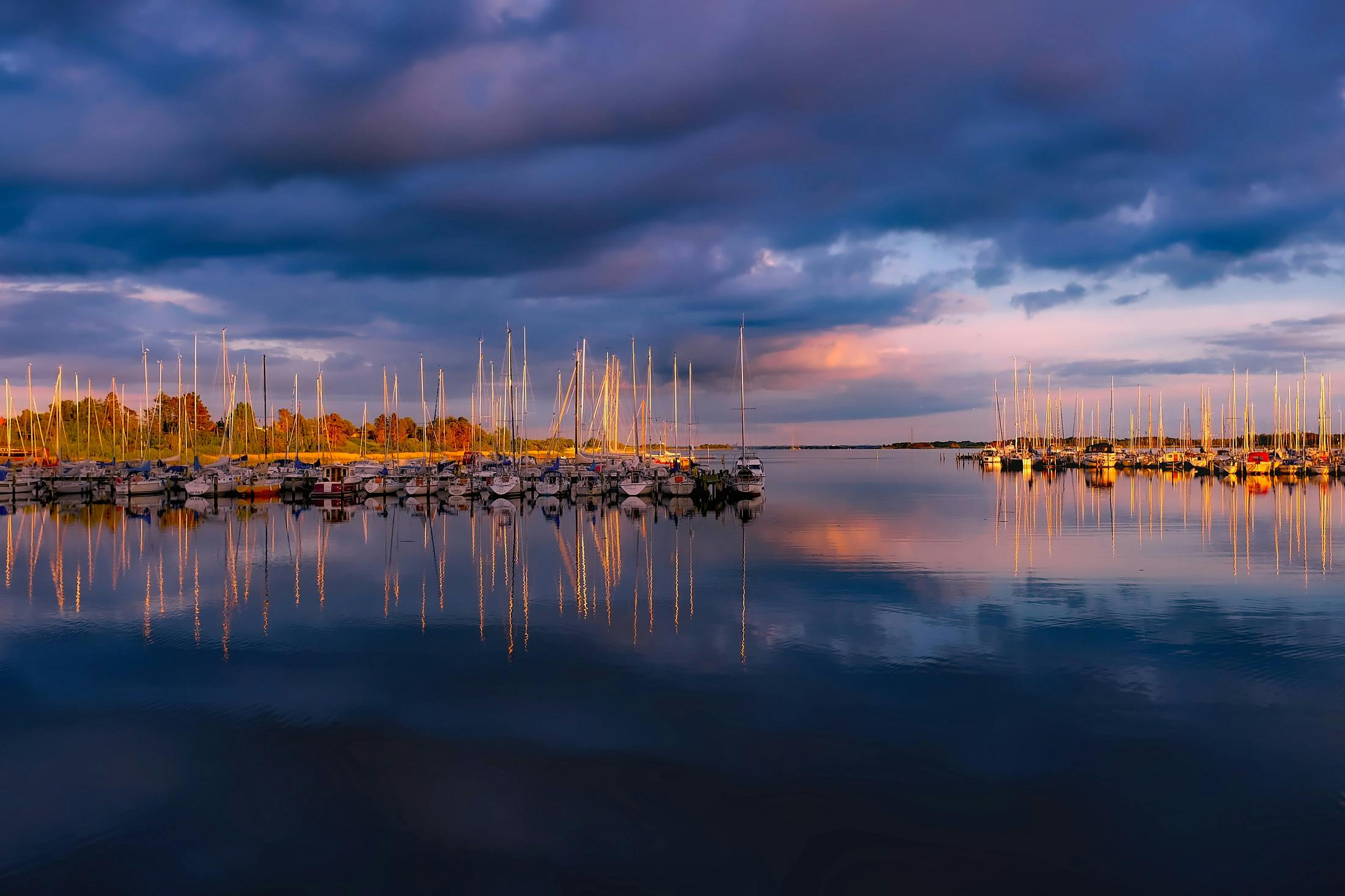 a harbor filled with lots of boats under a cloudy sky, a picture, by Robert Storm Petersen, pexels contest winner, autumn sunrise warm light, ultrawide landscape, thumbnail, shot on sony a 7 iii