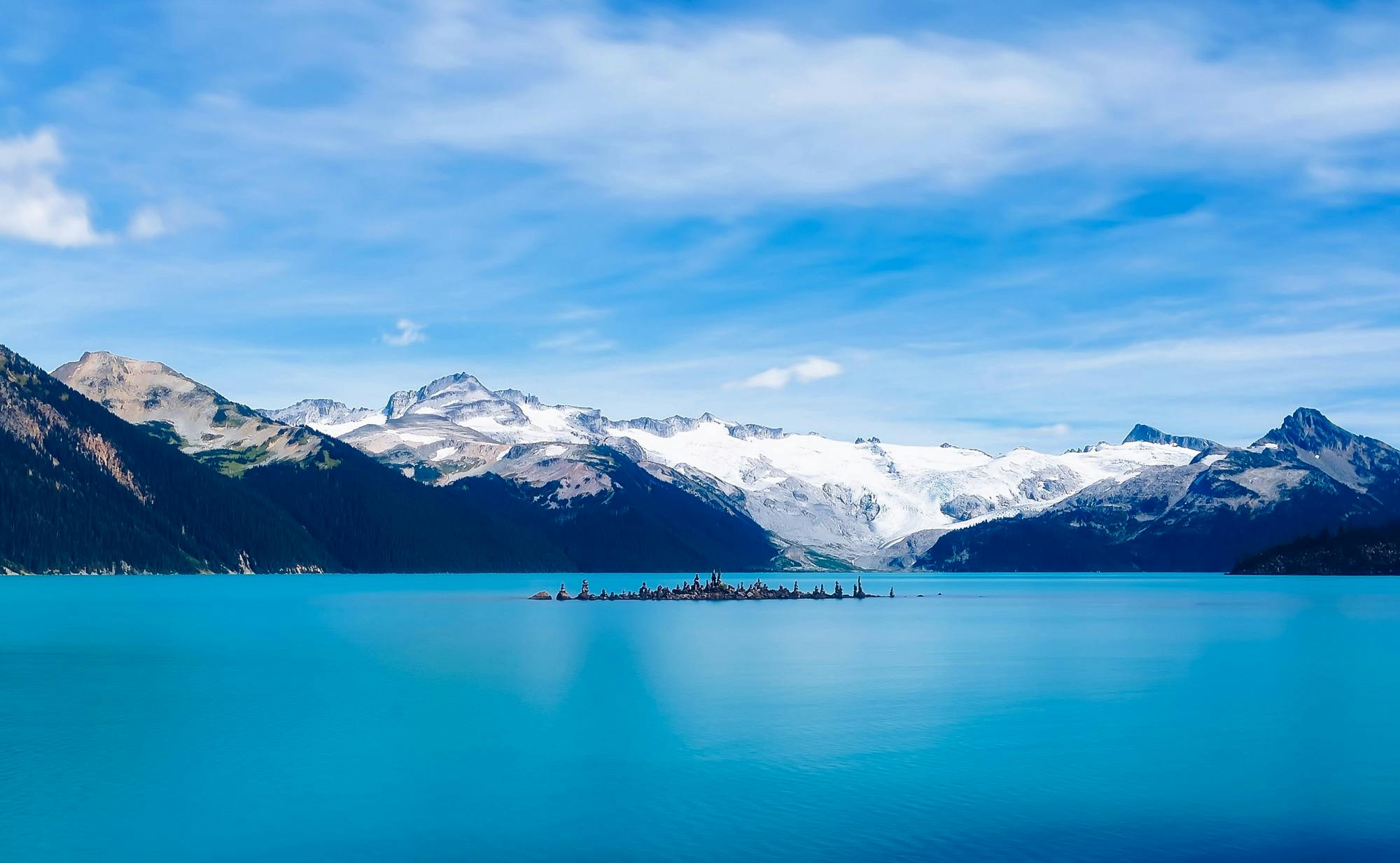 a large body of water with mountains in the background, by Doug Ohlson, pexels contest winner, blue glacier, whistler, multiple stories, island in a blue sea