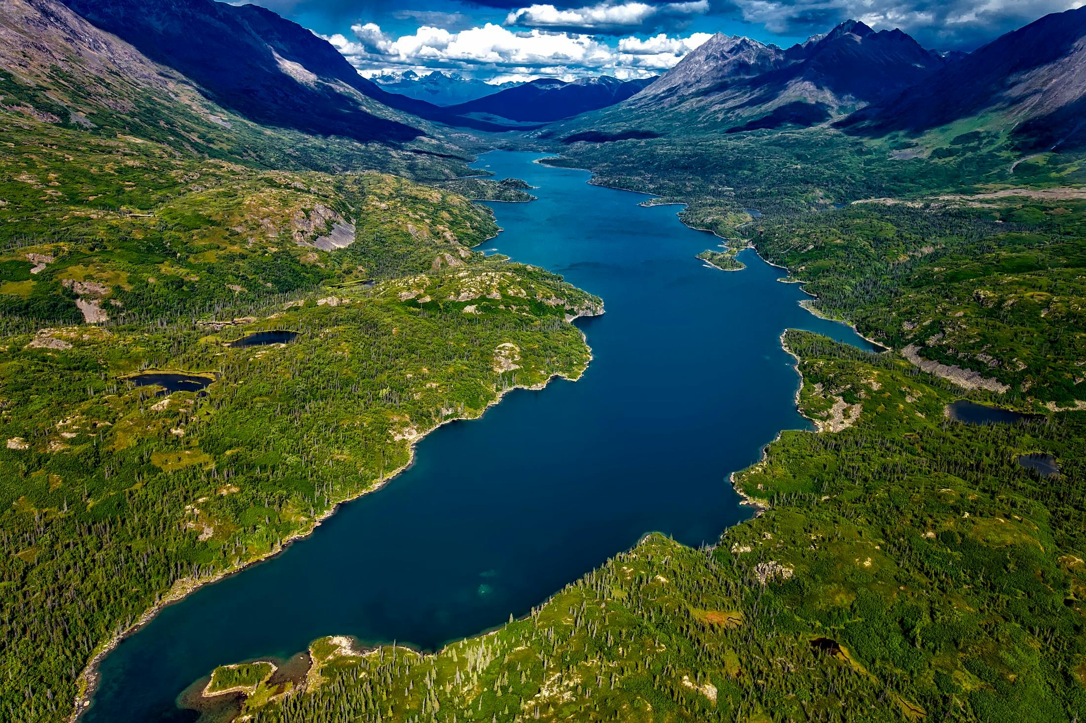 a large body of water surrounded by mountains, by Jim Nelson, pexels contest winner, aerial photo, fan favorite, bonnie maclean, lush surroundings