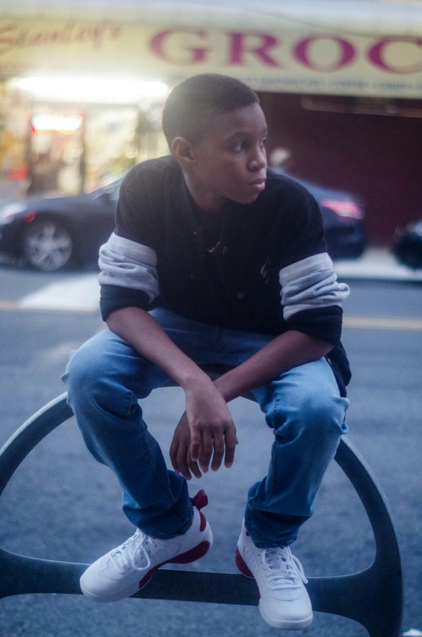 a young man sitting on top of a bench, by Andrew Stevovich, black teenage boy, tomboy, instagram photo, profile pic