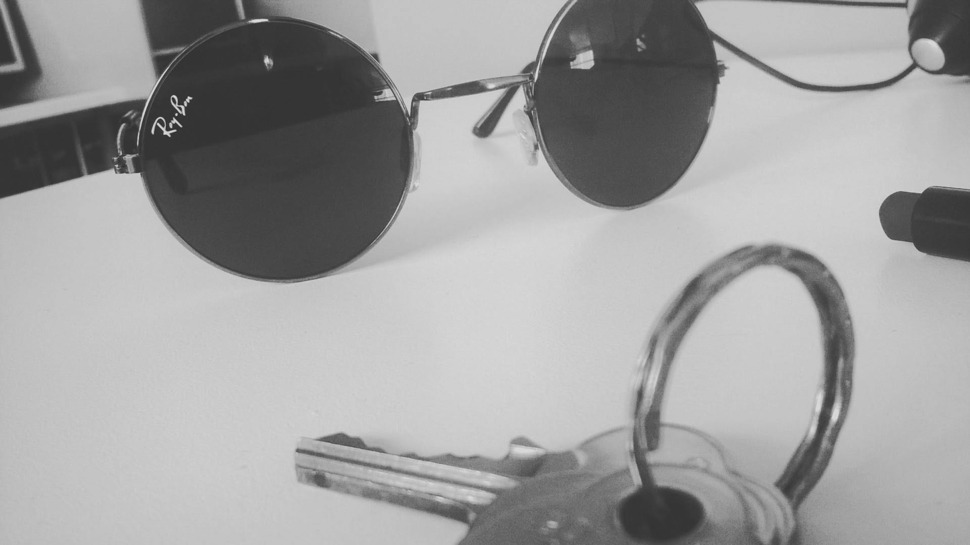 a pair of sunglasses sitting on top of a table, a black and white photo, metal key for the doors, highly detailed # no filter, round glasses potter, busted