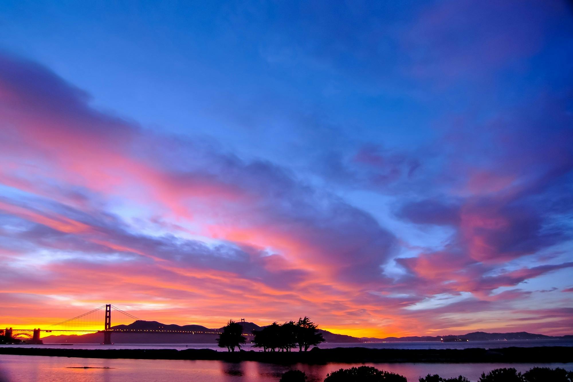 a beautiful sunset with the golden gate bridge in the background, unsplash contest winner, shades of pink and blue, panoramic, dramatic ”