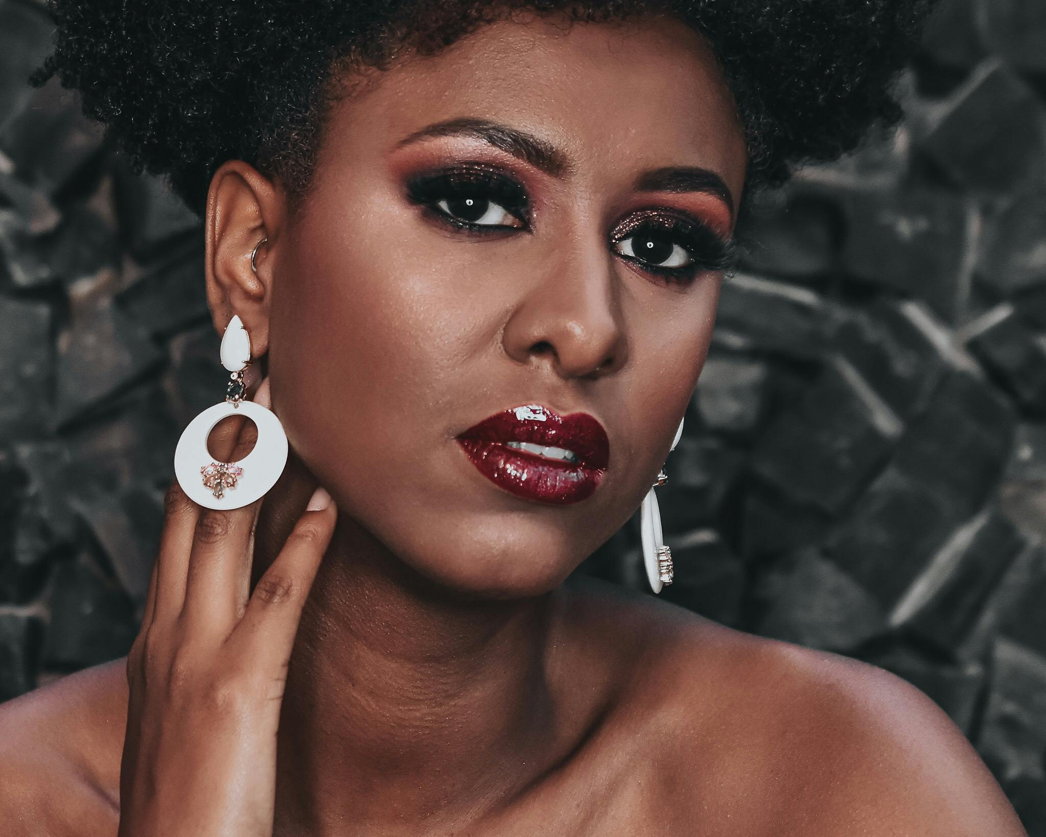 a woman with an afro is posing for a picture, inspired by Afewerk Tekle, trending on pexels, earrings, evening makeup, thumbnail, red brown and white color scheme