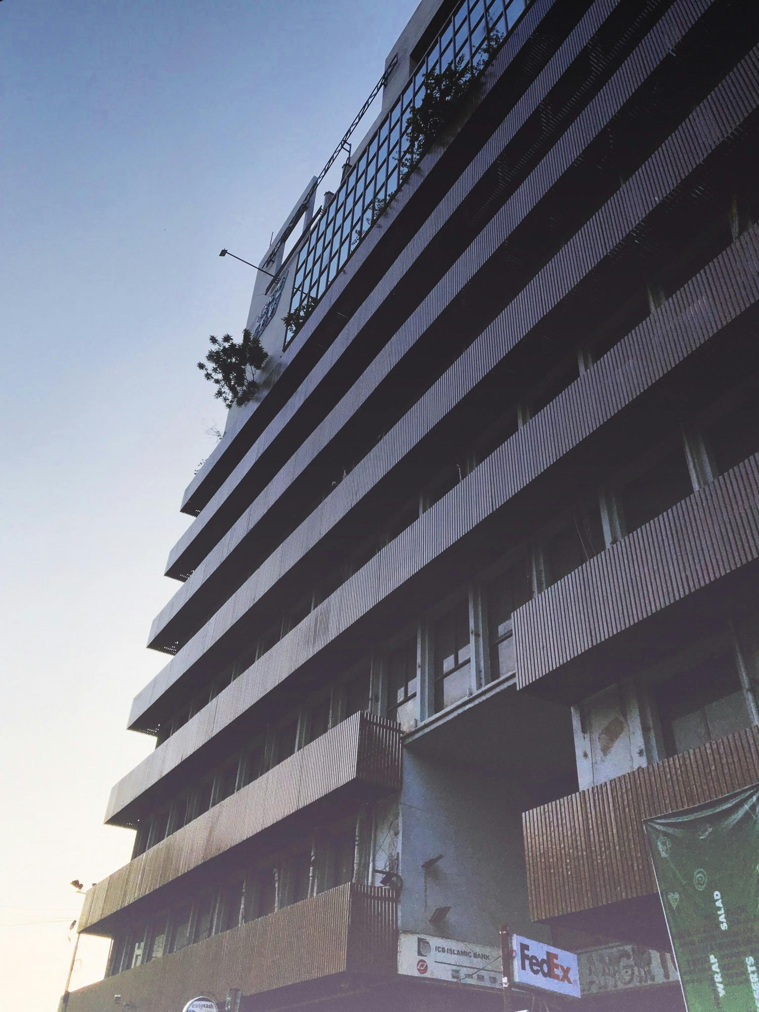 a tall building sitting on the side of a street, by Pablo Rey, brutalism, the empress’ hanging, low quality photo, burned, balcony