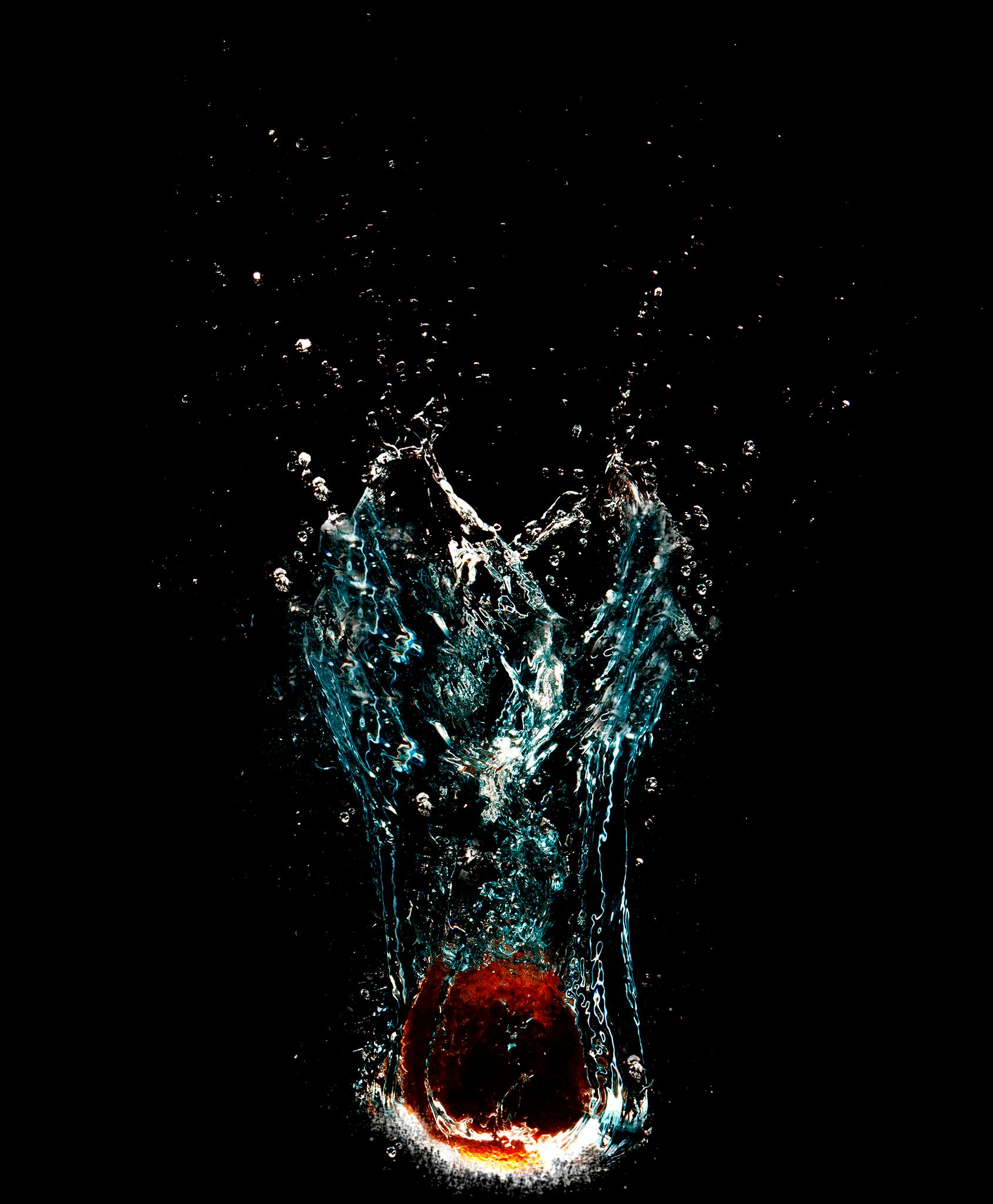 an apple falling into the water on a black background, an album cover, by Adam Chmielowski, unsplash, art photography, blue and red, drooling ferrofluid, tall, swimming