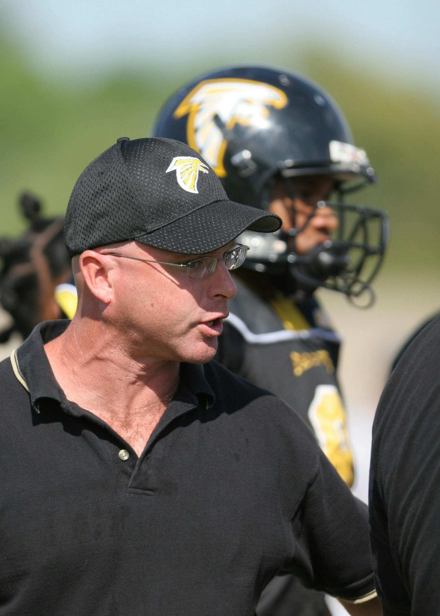 a group of men standing next to each other on a field, half helmet, yellow and black color scheme, kevin tighe with randy mantooth, focused