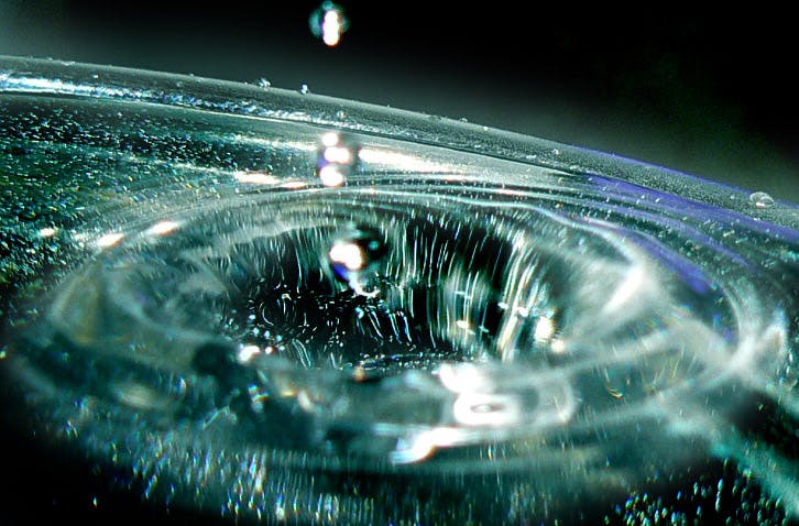 a close up of a water drop in a sink, flickr, holography, entering a quantum wormhole, droplets flow down the bottle, deeply hyperdetailed, glinting particles of ice